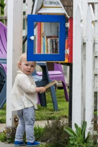 Toddler looking for books in a little free library 