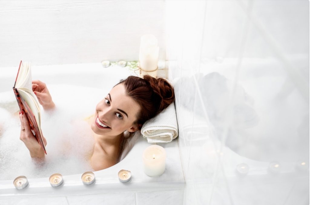 Woman reading in bubble bath 